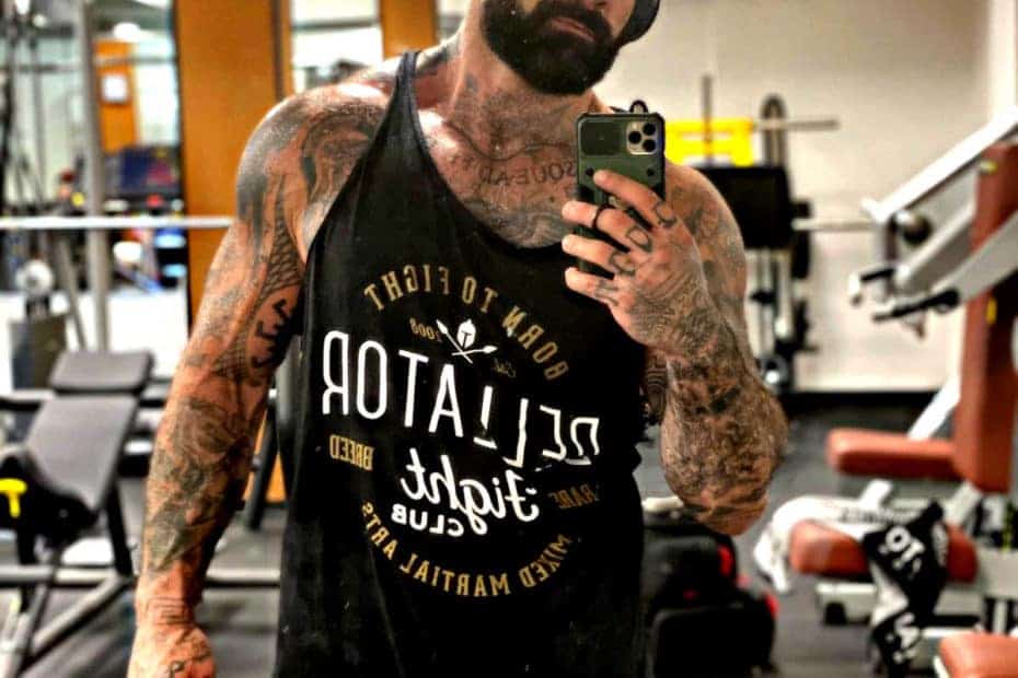 Un uomo che esegue esercizi di MMA in palestra mentre scatta un selfie con il telefono.