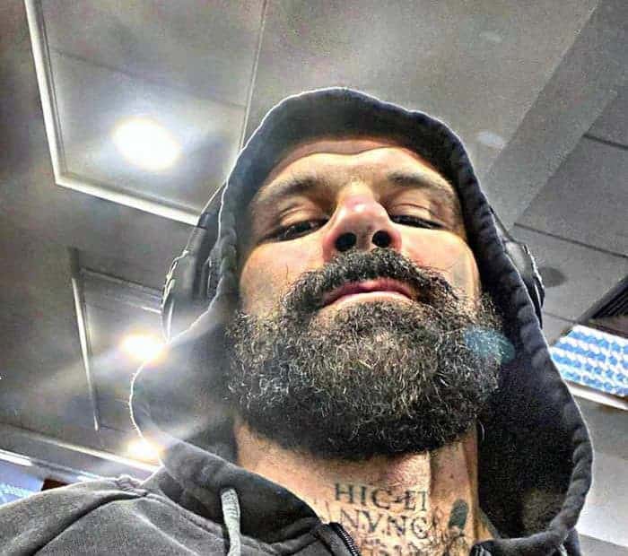 Un uomo con una cotta da mostro metabolico e tatuaggi.