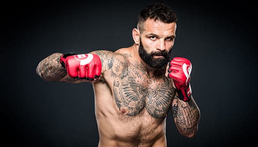 Un uomo con tatuaggi in posa per una foto.